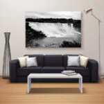 Black and white niagara falls canvas above a dark grey sofa with a wide coffee table and tall lamp