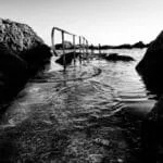 A monochrome photograph showcasing a stairway leading into water, evoking a sense of tranquility and intrigue