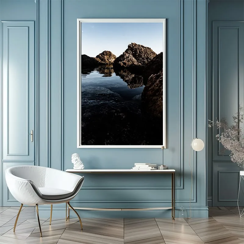 Framed photo of Ghar Lapsi coastline on blue wall with white armchair