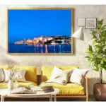 Valletta Skyline photo with yellow frame hanged above 2 yellow arm chair a coffee table and some books