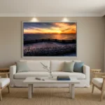 Minimalist coastal living room with light furniture and a large framed sunset seascape above the sofa.
