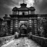 beautiful stone archway of Mdina Gate in Black and White, with a clock tower visible in the background, blending history and charm