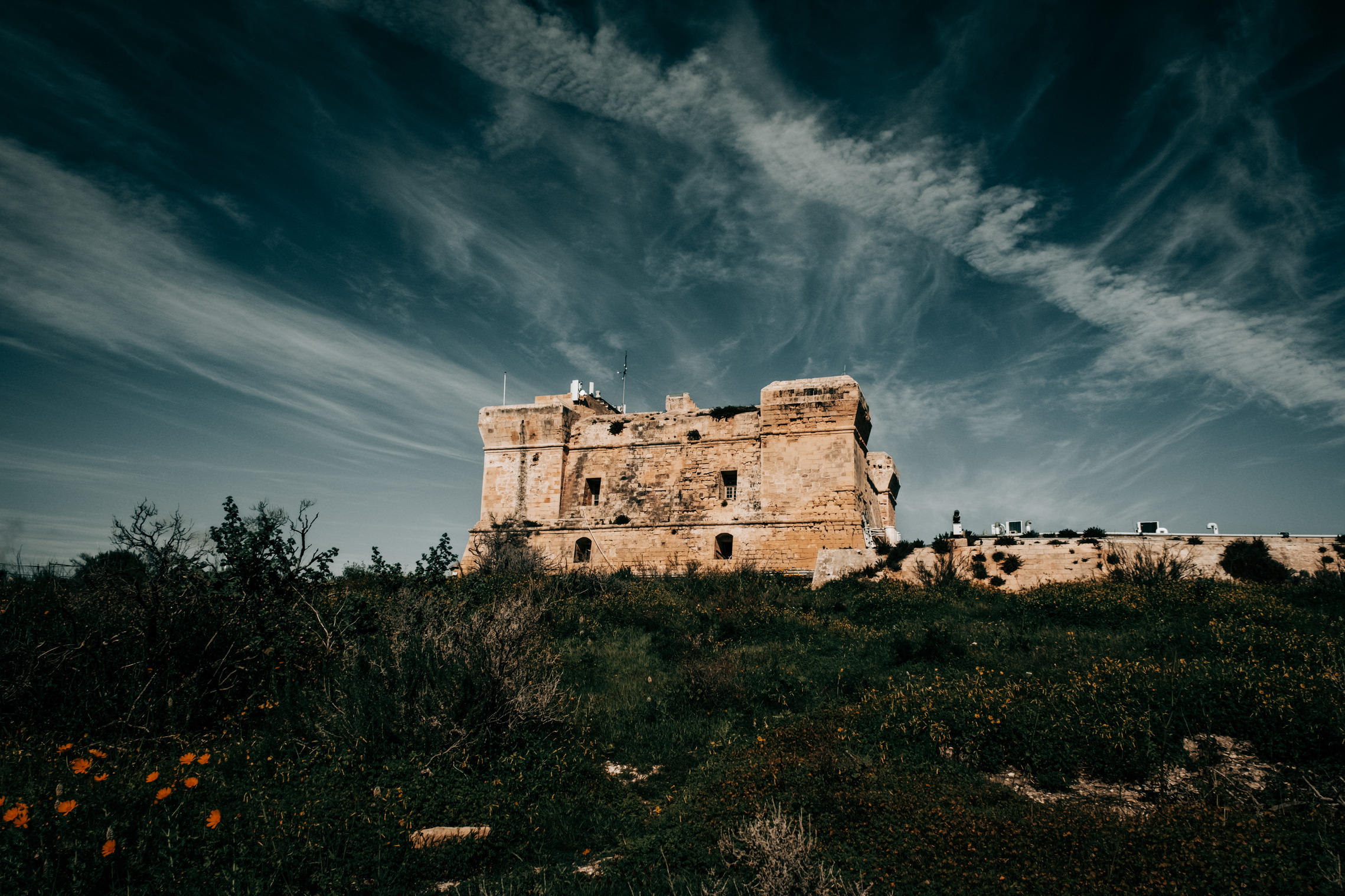 The historic San Lucian fort in Malta, perched on a hill, under a sky adorned with clouds.