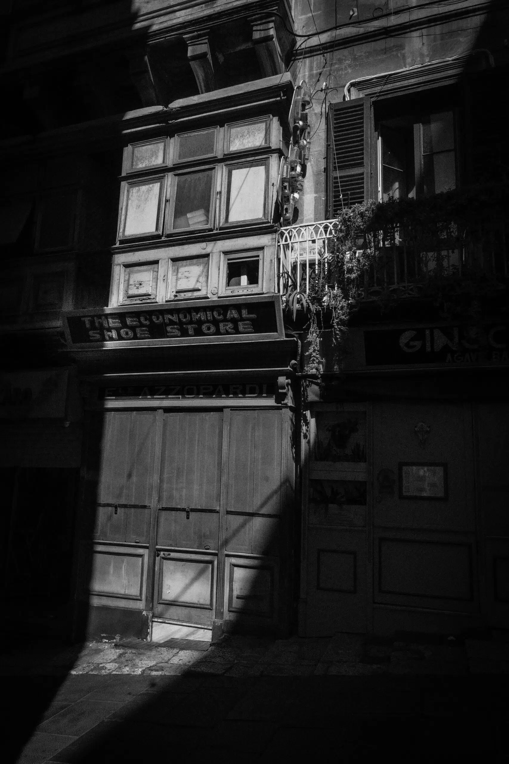 A monochrome photograph showcasing a building with a prominent shadow, emphasising its structure and design in Valletta Malta