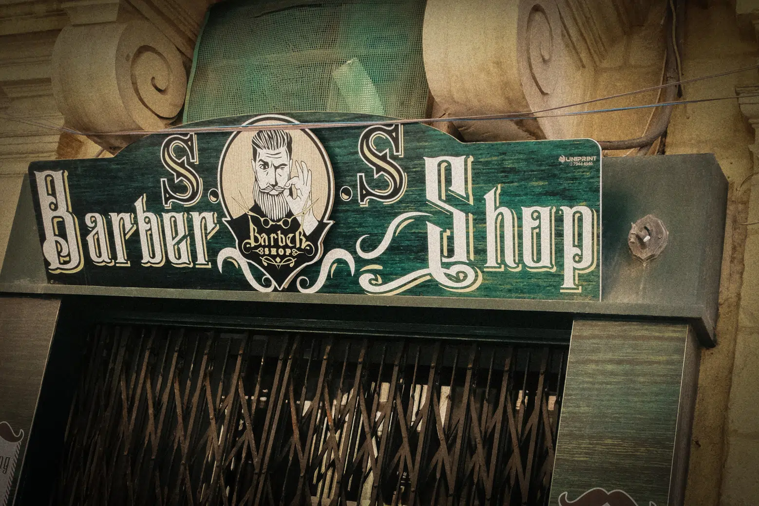 A vintage sign on a building in Valletta displaying the words Barber Shop," reflecting the charm of an old establishment.