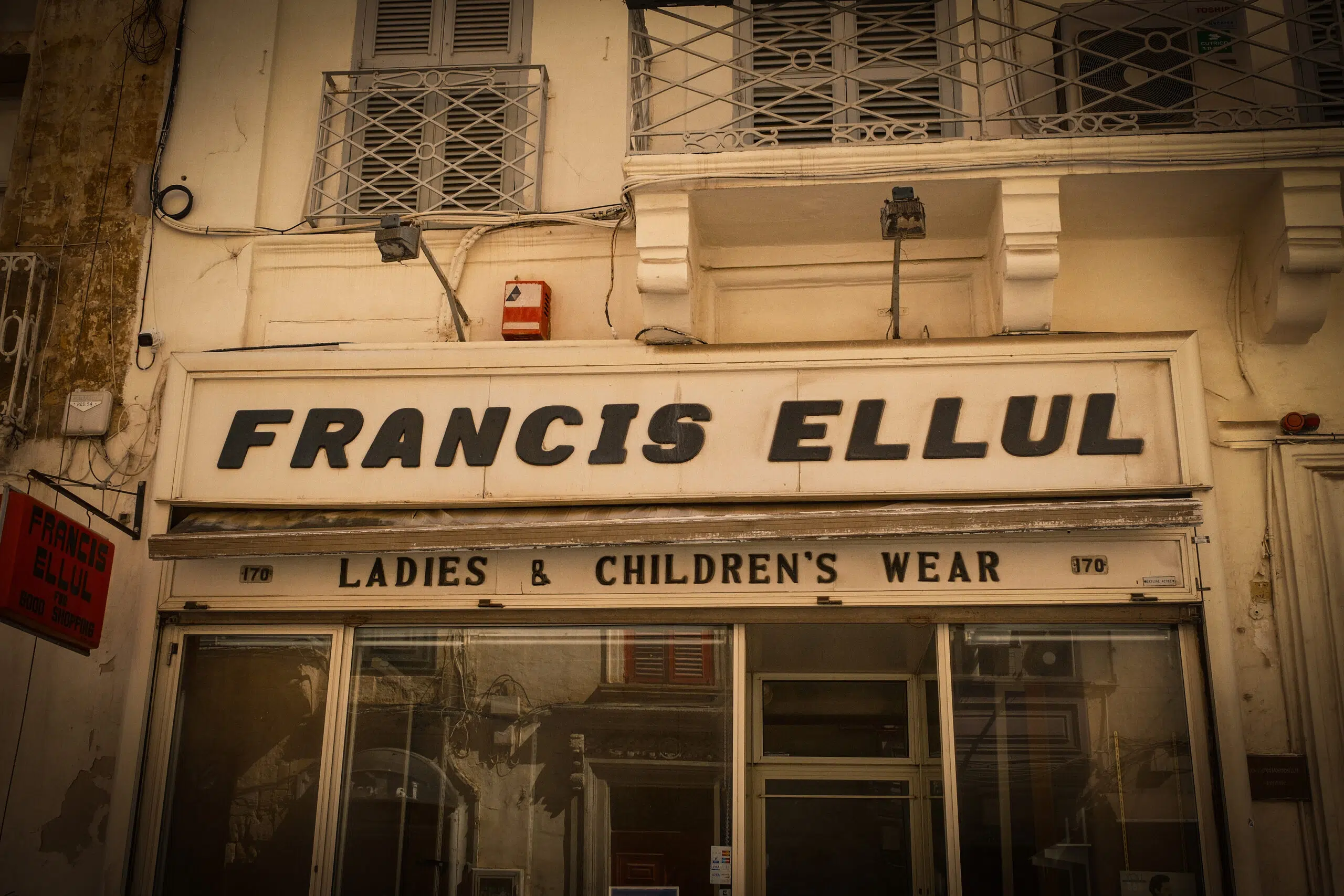 A building in Valletta featuring a sign that reads "Francis Ellul," now closed, previously a ladies' and children's wear store.