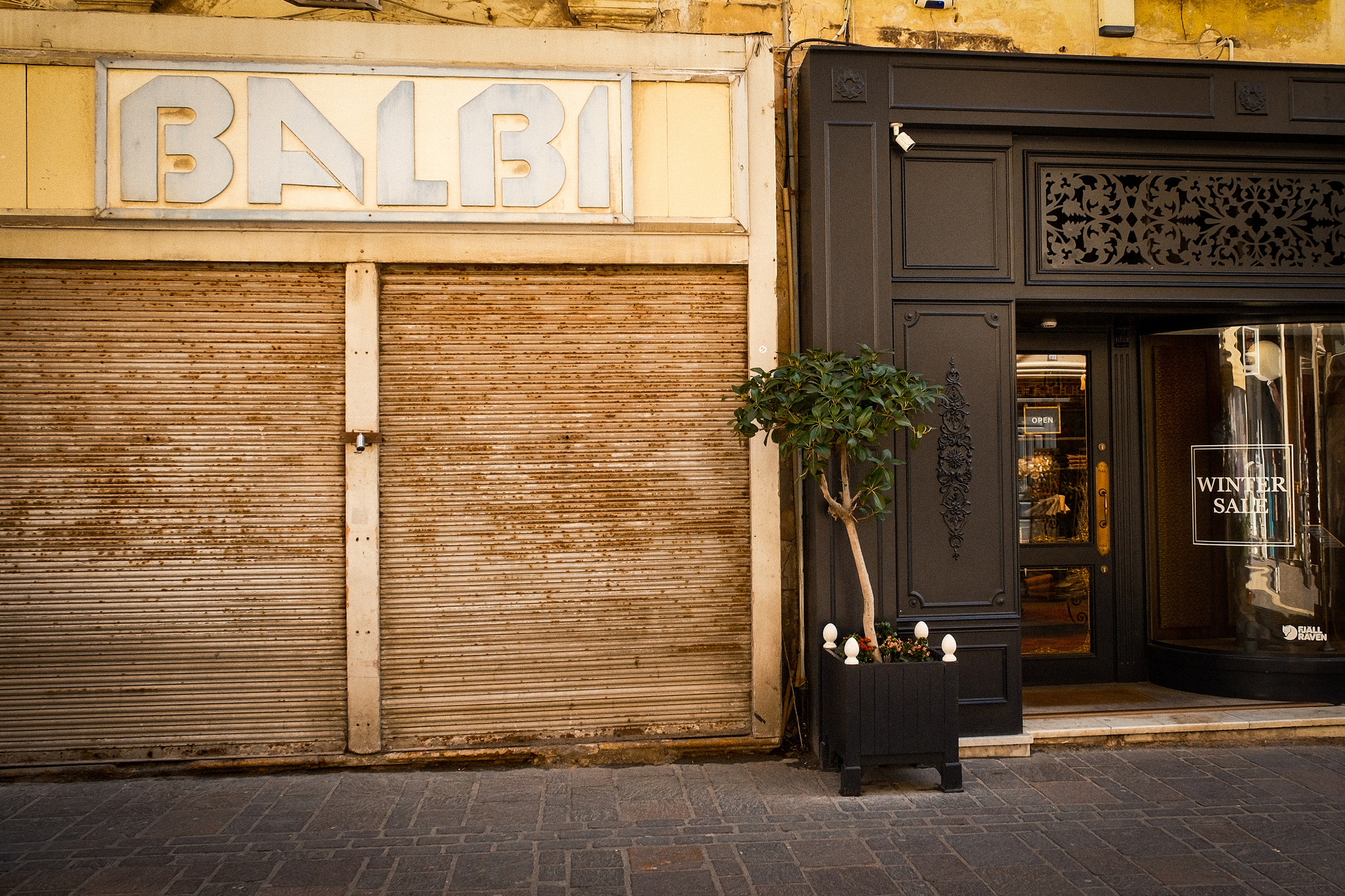 In Valletta, a black and yellow building, the old Balbi shop, juxtaposes with a new shop nearby, showcasing architectural diversity.