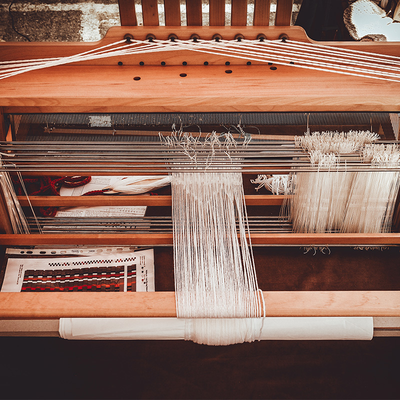 Traditional Maltese weaving loom with white threads and yarn tools.