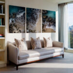 Three large paintings depicting the Gozo shoreline, showcasing ocean waves and a beach, displayed in a living room setting.