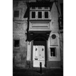 White wooden doorway with commemorative plaque in Rabat, Malta.