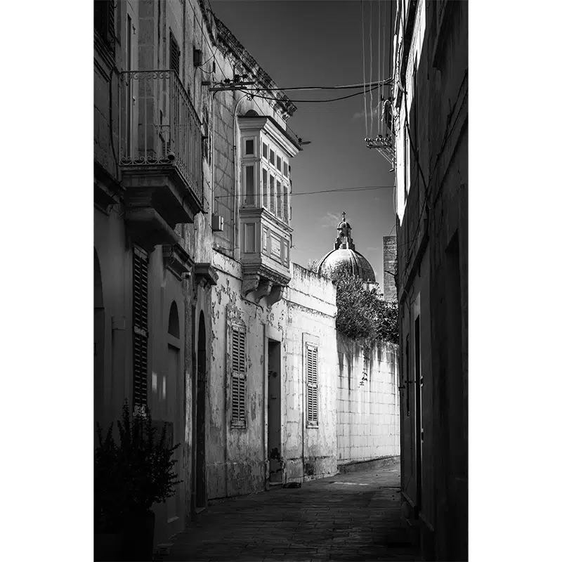 Street view in Rabat leading to a distant church dome.