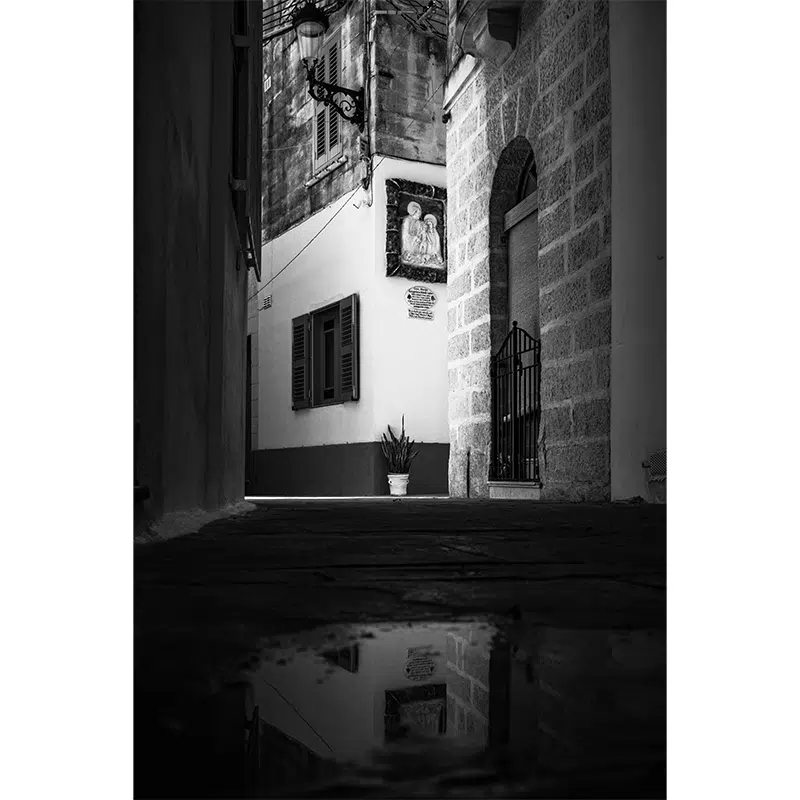 Reflection of balconies and facades in a puddle on a Rabat street.