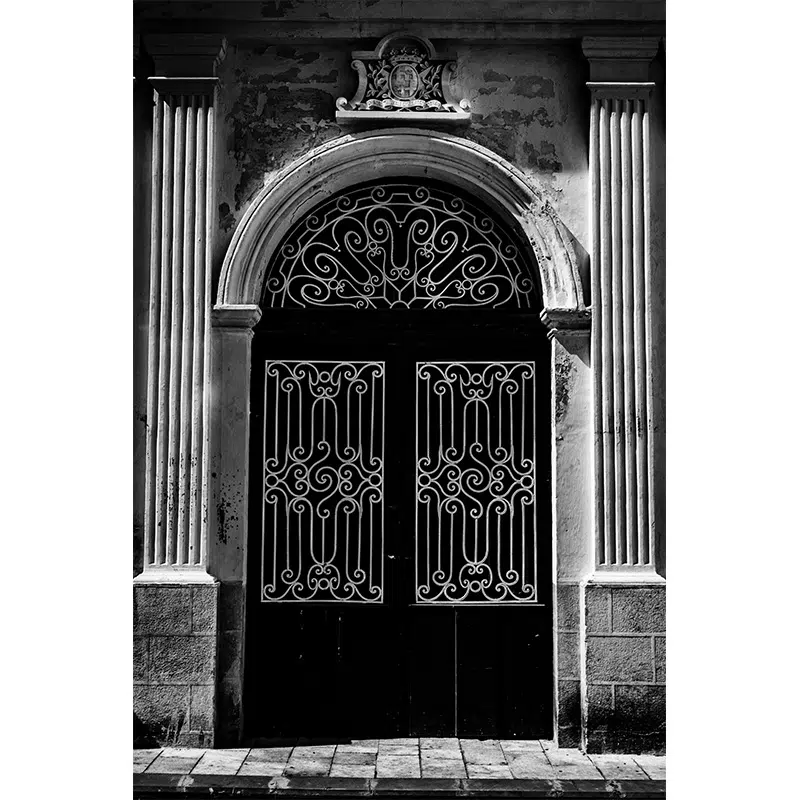 Ornate wrought iron door framed by classical columns in Rabat, Malta.