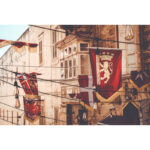 Red and white Valletta flags and festive lights hanging in a Maltese street.
