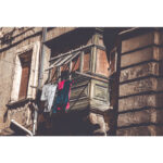Maltese wooden balcony with hanging laundry and open blinds, Valletta