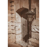 Weathered wooden door with classic lantern on the limestone walls of Selmun Palace, Malta.