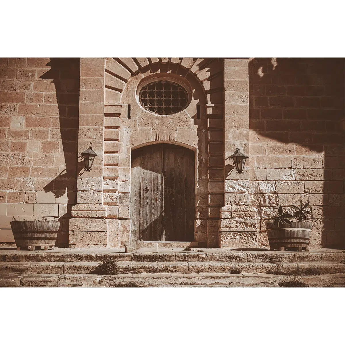 Grand stone steps and arched doorway at Selmun Palace, Malta, in sunlight.