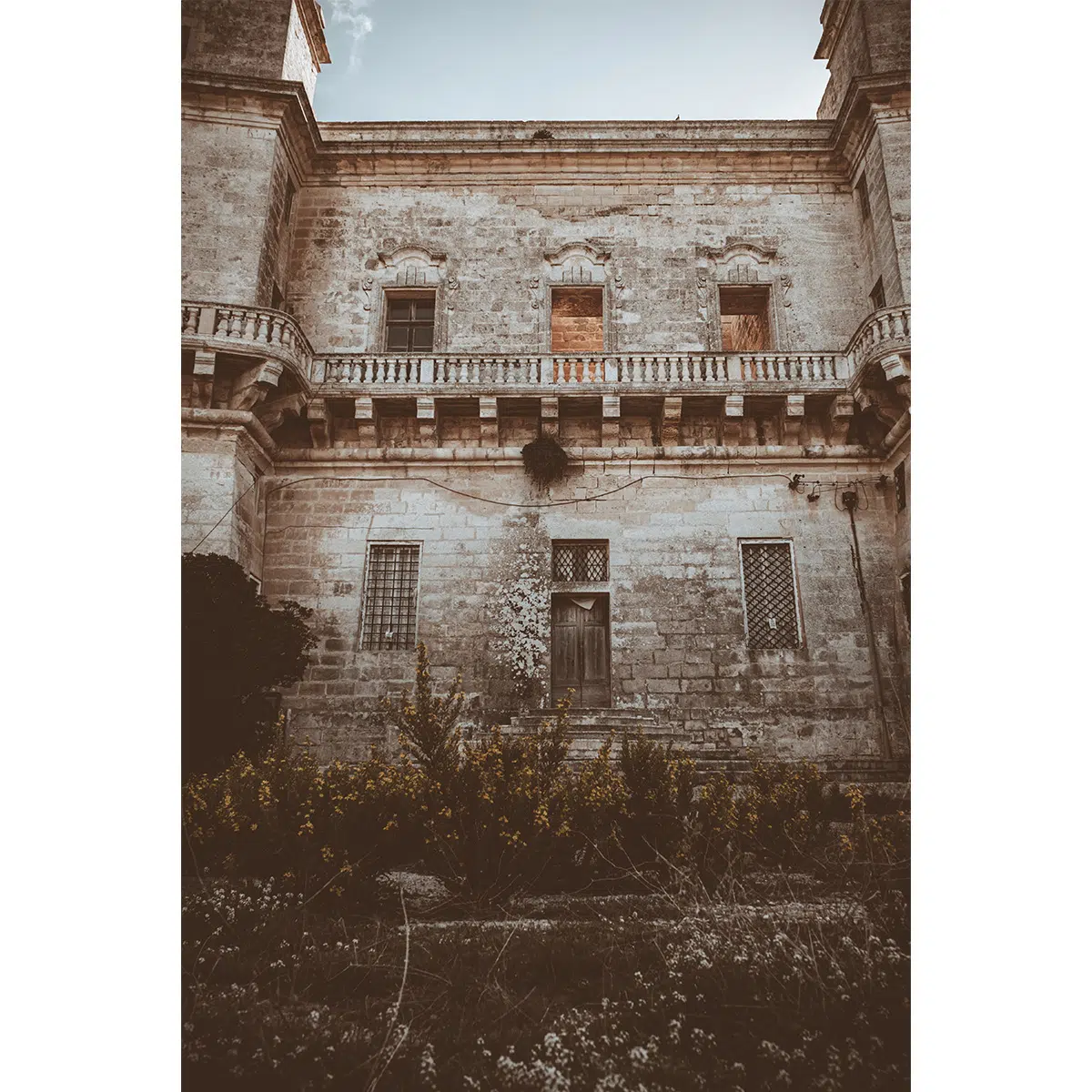 Weathered stone wall with barred windows at Selmun Palace, Malta.