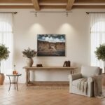 A person in a modern living room looking at a framed print of the Gozo Qbajjar Battery Gateway on a white wall.
