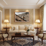 A beautifully sunlit room with minimalist decor features a large, framed print of the Malta Mdina Stone Parapet centered above a light grey sofa, complemented by a natural wood side table with a simple ceramic vase.