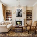 A man in a modern living room looking at a framed print of the Rabat Malta Augustinian Friars Facade hanging on a white wall above a minimalist sofa.