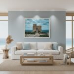 A person stands on a rocky beach at dusk, gazing at the Dwejra Tower under a twilight sky. The scene is illuminated by the soft glow of the blue hour, highlighting the tower's historic architecture and the rugged coastline.