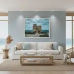 A person stands on a rocky beach at dusk, gazing at the Dwejra Tower under a twilight sky. The scene is illuminated by the soft glow of the blue hour, highlighting the tower's historic architecture and the rugged coastline.