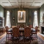 A large framed print of the Valletta Malta Grand Harbour Hotel Steps hangs on a light gray wall above a minimalist white and wood sideboard, with a green plant in a terracotta pot providing a pop of color to the modern living room setting.