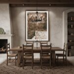 A living room with a neutral color scheme featuring a large framed print of Valletta, Malta old doors and arches hanging above a light-colored sofa with throw pillows, a wooden coffee table with books, and a plant in the corner.