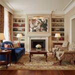 A beautifully adorned Maltese balcony, with intricate stone carvings, vibrant potted plants, and traditional wooden shutters, extends from a historic limestone building. The afternoon sun highlights the architectural details and textures. The scene is set in a charming, narrow street in Valletta, with other similar balconies and traditional street lamps visible in the background, conveying a sense of historic European architecture and Mediterranean charm.