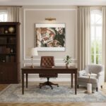 A large, ornate stone balcony, characteristic of Maltese architecture, juts out from a warm, honey-colored stone building. The balcony is adorned with intricate carvings and supported by decorative corbels. Various potted green plants are arranged on the balcony, adding a touch of life and color. In the background, other traditional buildings with similar architectural styles can be seen under a bright, clear sky. The scene evokes a sense of historical charm and Mediterranean ambiance. This image is a mockup showcasing how the 'Valletta Malta Ornate Stone Balcony - Wall Art' would appear in a home or office.