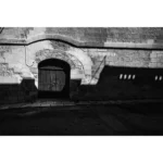 Arched wooden door in stone wall with shadows