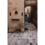 Narrow stone alley with archway and religious icon