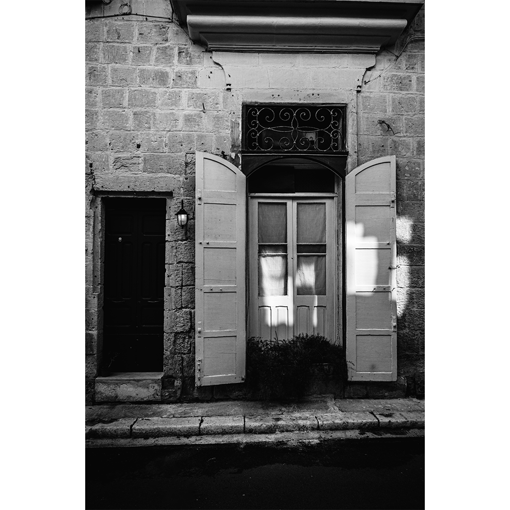 Open shutters on stone building facade in black and white