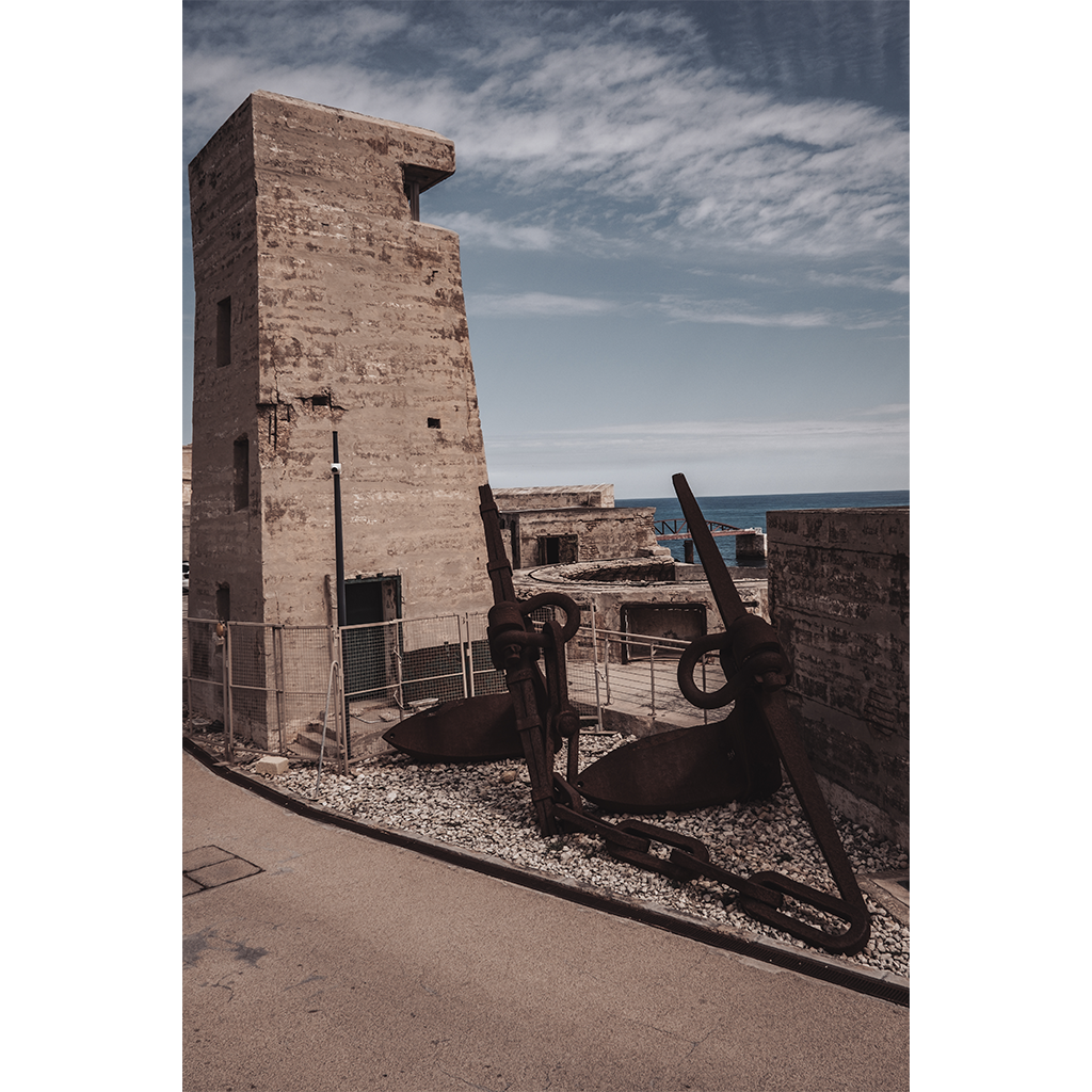 Rusted anchors beside coastal concrete fort tower