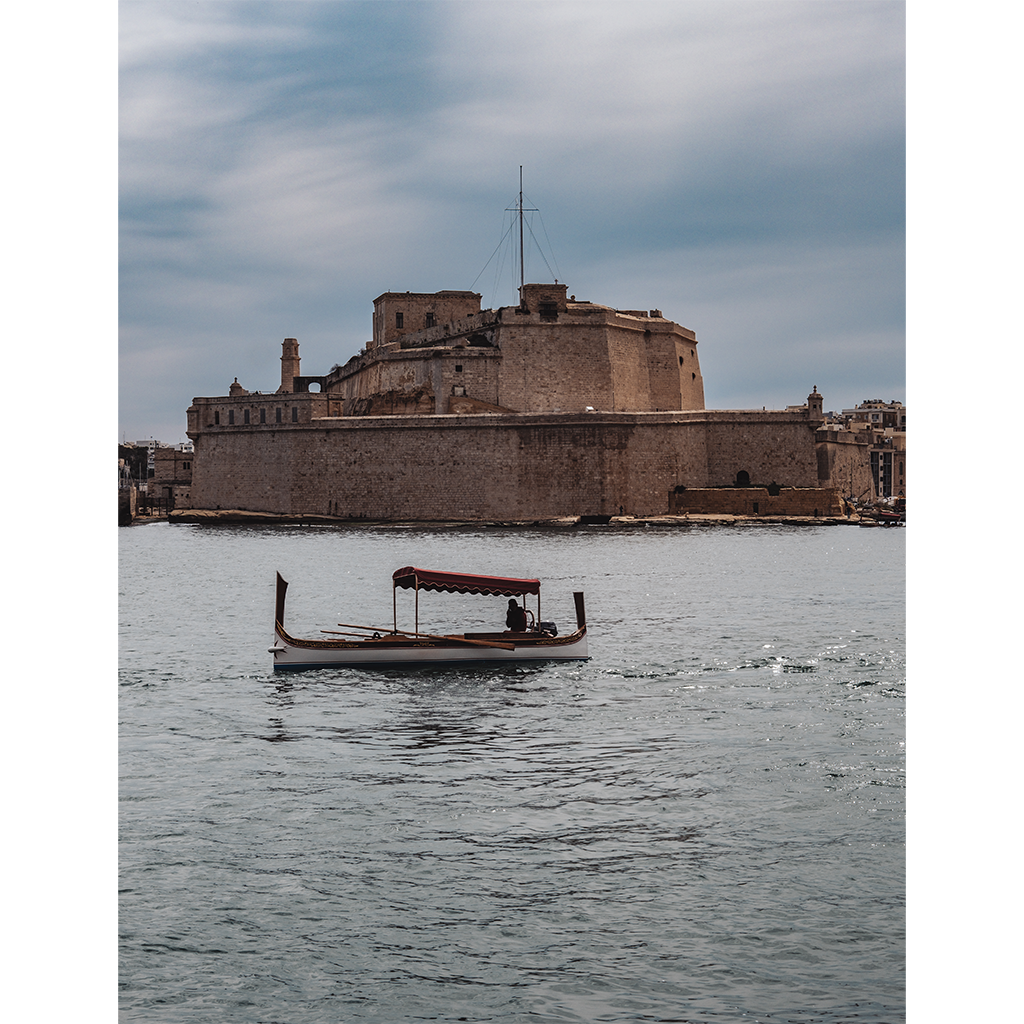 Small boat passing historic stone fortress by water