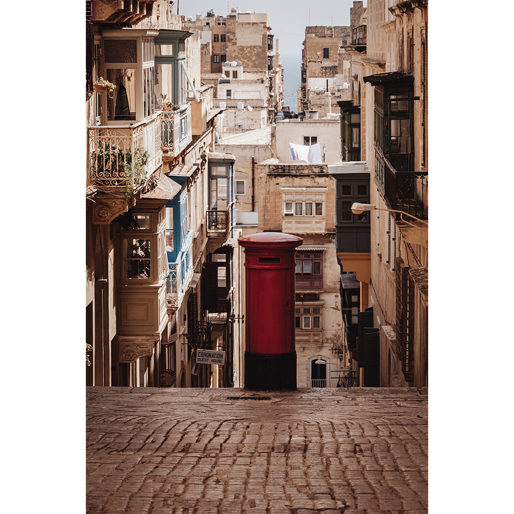 Red post box on narrow cobblestone street