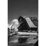 Waves crashing against curved concrete bridge in black and white