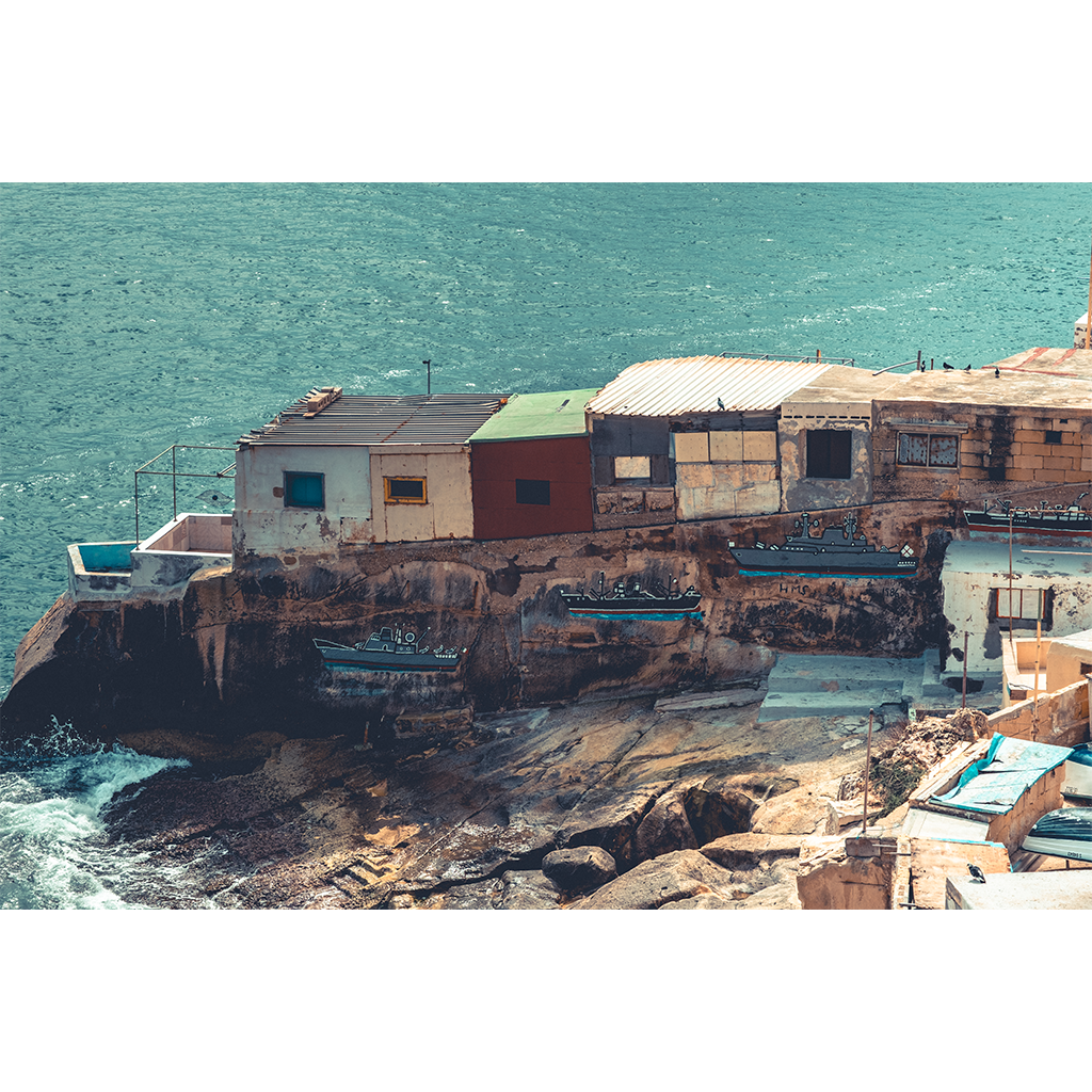 Seaside buildings with ship murals on rocky cliff