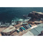 Small boats stored beside rocky ocean shoreline