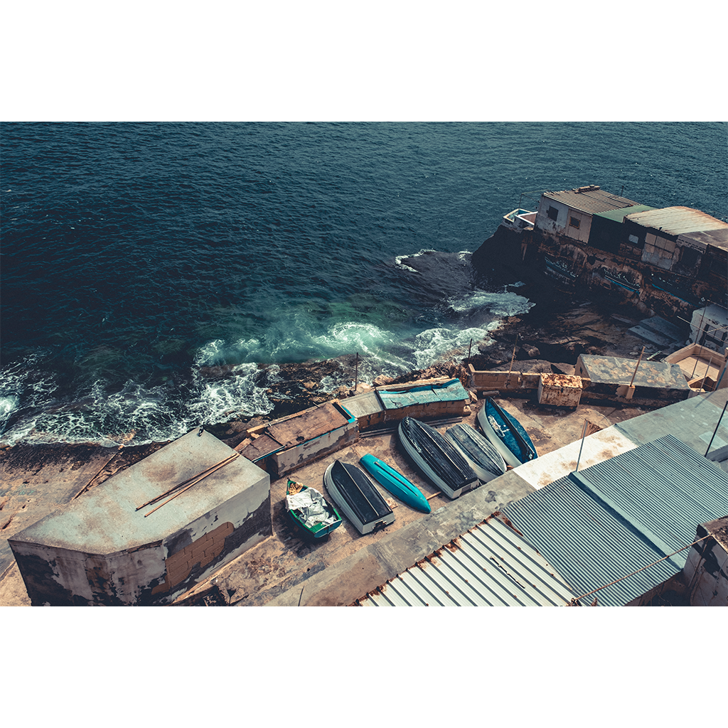 Small boats stored beside rocky ocean shoreline