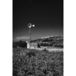 Black and white rural windmill on hillside field