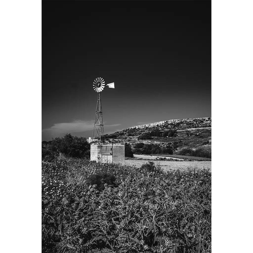 Black and white rural windmill on hillside field