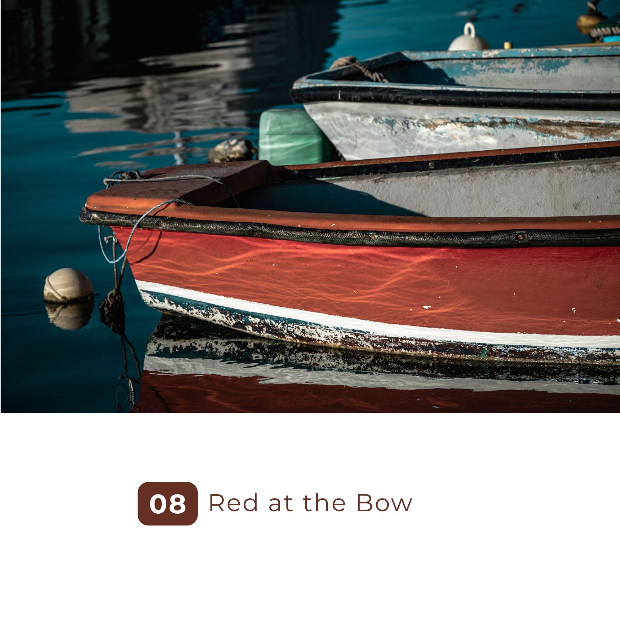 Weathered red boat bow moored on calm blue water