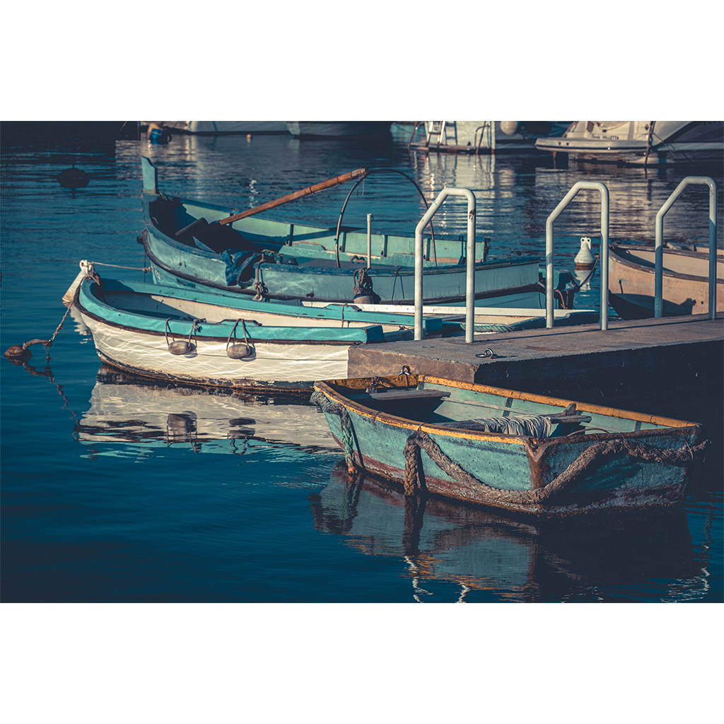 Weathered rowboats moored beside a dock on calm water
