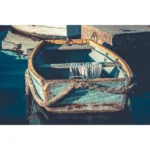 Weathered turquoise rowboat moored beside a dock