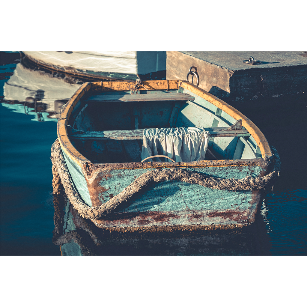 Weathered turquoise rowboat moored beside a dock