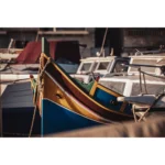 Colorful traditional fishing boat moored among white motorboats