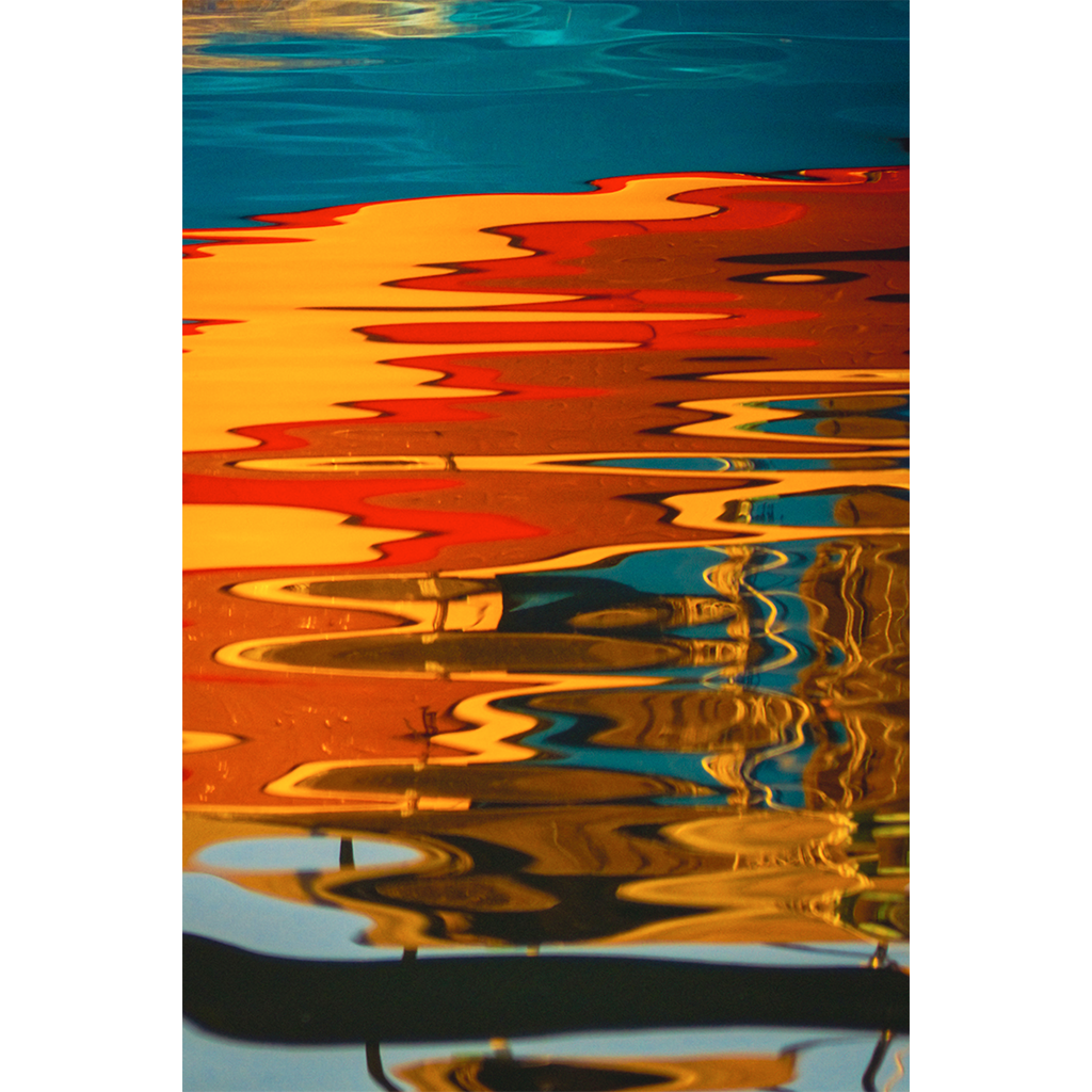 Colorful boat reflections rippling across blue water