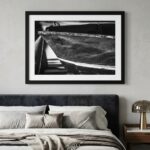 Black-and-white boat photograph above modern upholstered bed
